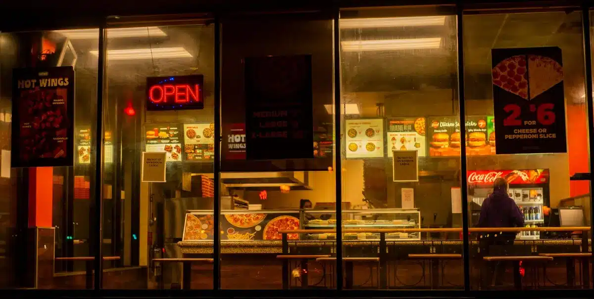 Pizzeria-Theke mit Kunden, die am späten Abend Speisen abholen