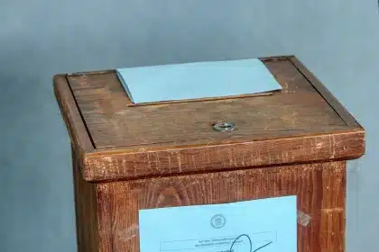 Folded referendum leaflet and blank ballot on a kitchen table, hands visible