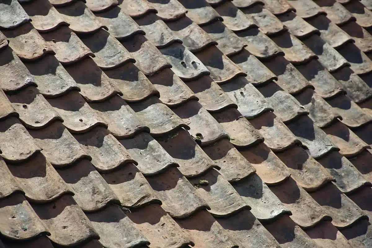 Artisans working with clay tiles and bundles of rice straw in a workshop