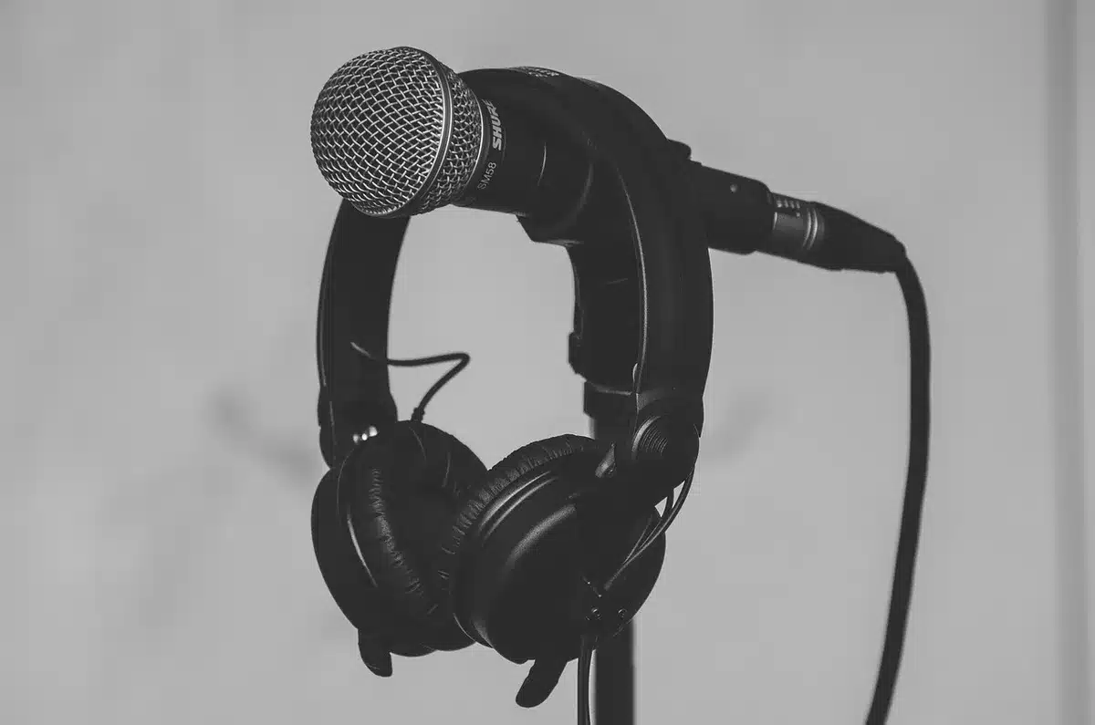 Silhouetted podcasters around microphones and laptops in a small studio
