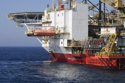 Offshore platform and supply boat on the North Sea with anonymous hands on a railing