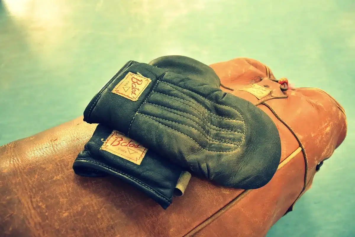 Worn punching bag and taped gloves in a training gym, evoking combat sports finance debate