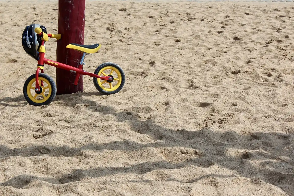 Children wearing helmets learning bike skills with volunteers on a closed course